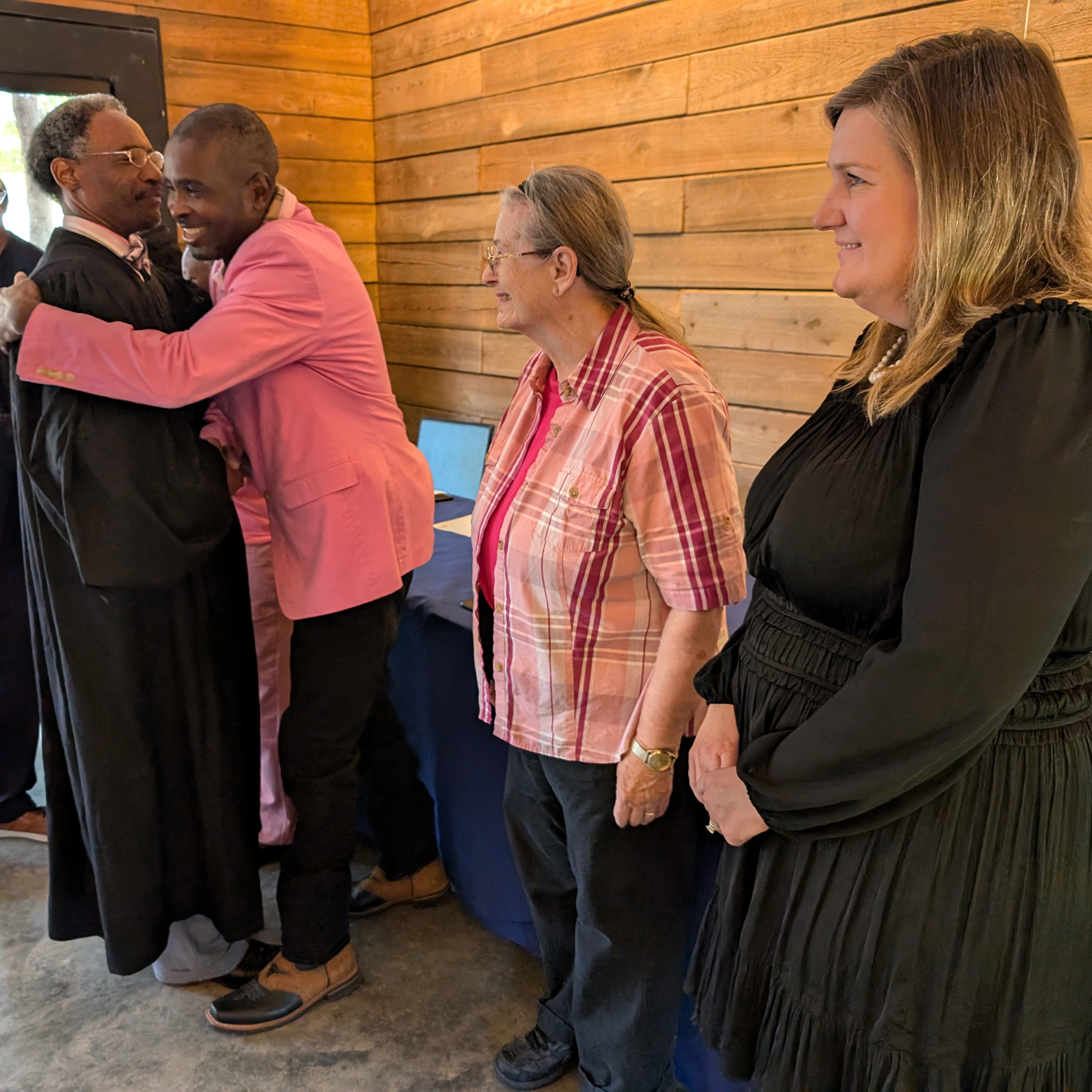 two people share a hug while two others look on