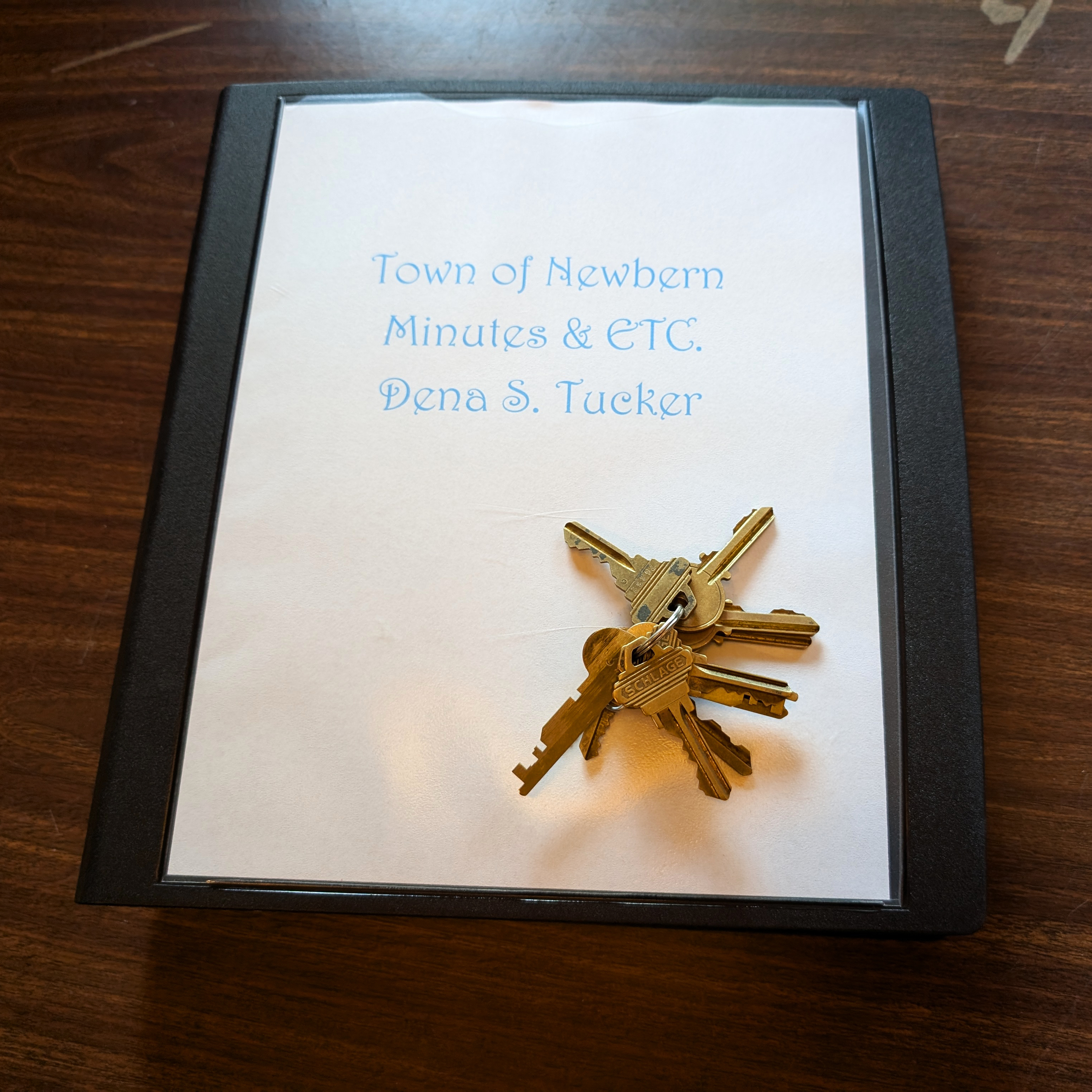 A set of keys sit on a black folder that reads "Town of Newber Minutes & etc. Dena S. Tucker."