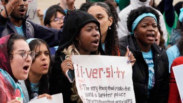 Young people hold signs uplifting diversity.