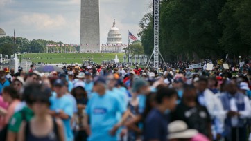 Blurred foreground of crowd with clear view of monuments and buildings on National Mall in background.