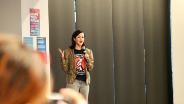 Person holding microphone in front of crowd.