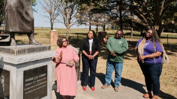 Group of people gathered at the foot of a statue.