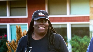 Wearing a hat that reads, "Be a Voter," Yterenickia Bell walks outdoor.