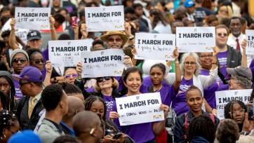 People outside hold signs "I March for" to honor others during the 59th anniversary of Bloody Sunday.