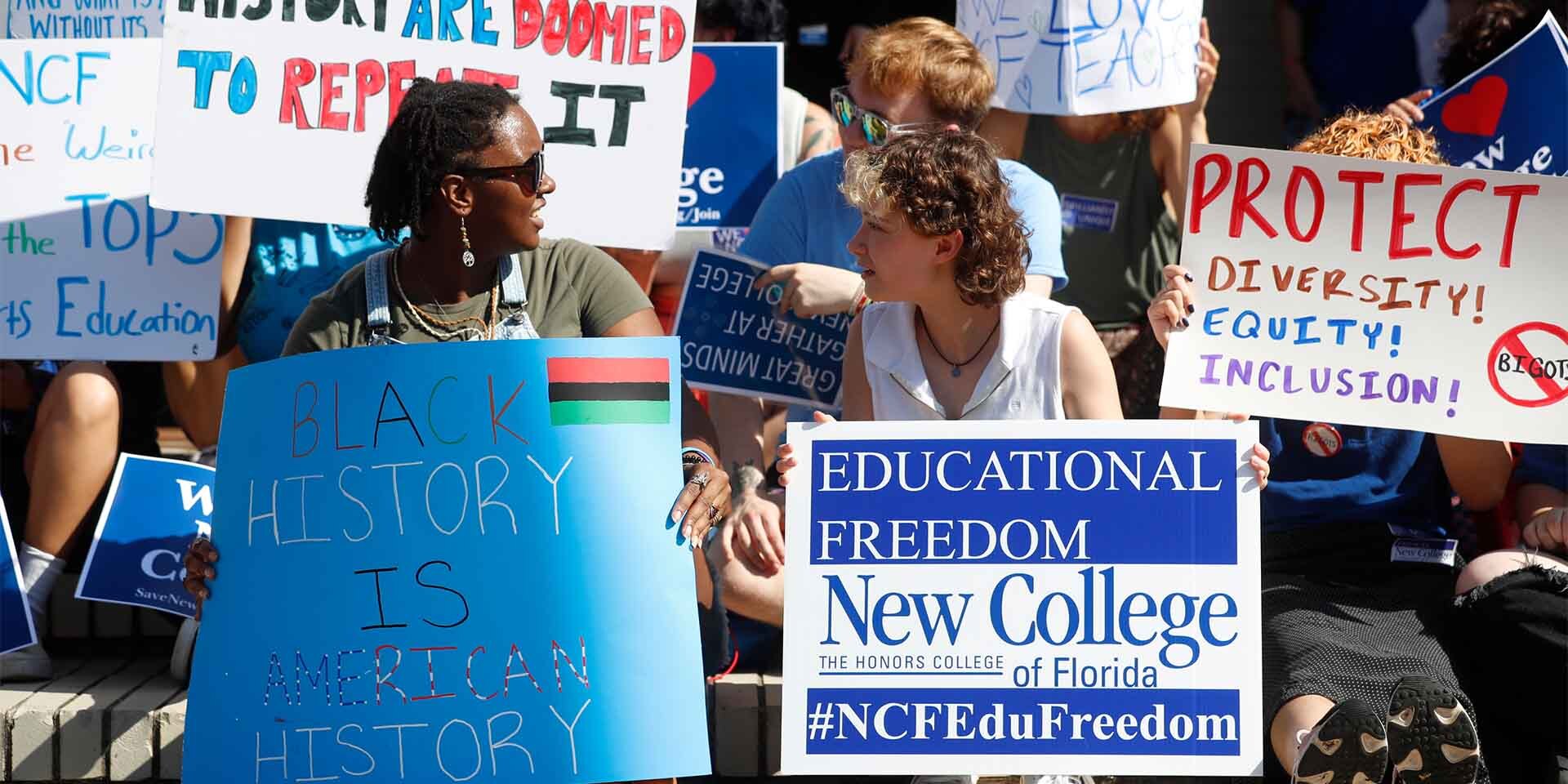 Group of people holding signs related to teaching.